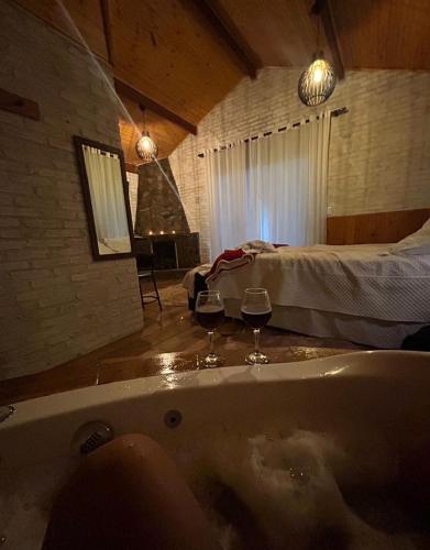 a bathroom with a tub and two glasses of wine at Chalé Sonho Diniz 3 in Monte Verde