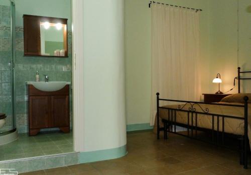 a bathroom with a sink and a bed and a mirror at La Casa dellAmericano - Casa d'epoca anni '30 in Aliano
