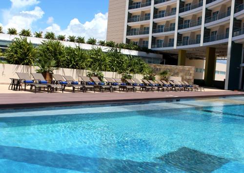 uma piscina com cadeiras e um edifício em Krystal Urban Cancun & Beach Club em Cancún