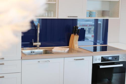 a kitchen with white cabinets and a sink at Prora Block 1 - Sauna, Pool und Fitness - Meerzeit in Binz