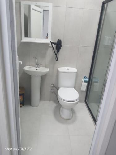 a white bathroom with a toilet and a sink at Tekirdağ Begonya Hotel in Kapaklı