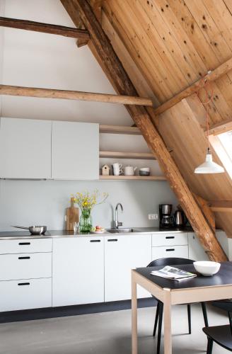 a kitchen with white cabinets and a table at It Buterhus in Balk