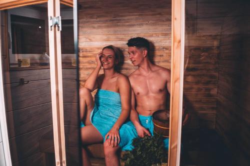a man and a woman sitting in a sauna at Hõbekala Guesthouse in Kalana