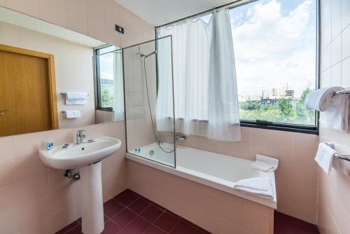 baño con lavabo, bañera y ventana en Sotel Nomentana Roma, en Roma