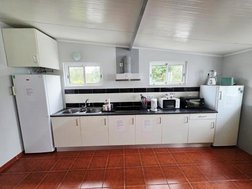 a kitchen with white appliances and white cabinets at Monte Família Ferreira in Vale de Açor