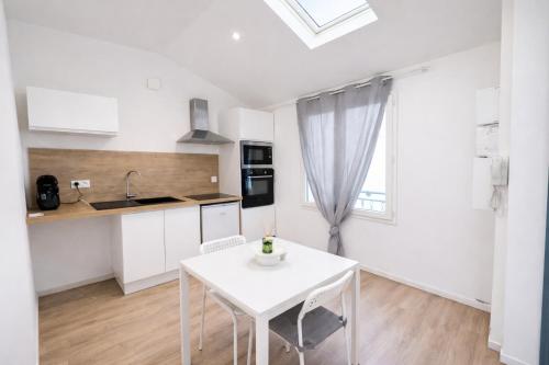 Le cocon - STUDIO- MACON في Saint-Laurent-sur-Saône: مطبخ أبيض اللون مع طاولة بيضاء ونافذة