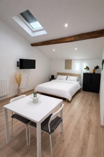 a bedroom with a white bed and a table and a bed at Le cocon - STUDIO- MACON in Saint-Laurent-sur-Saône
