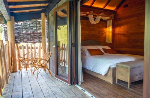 a bedroom with a bed on a wooden porch at Nigloland Hôtels in Dolancourt