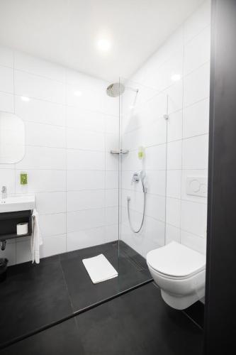 a white bathroom with a toilet and a shower at N9 Hotel Nürnberg-City in Nuremberg