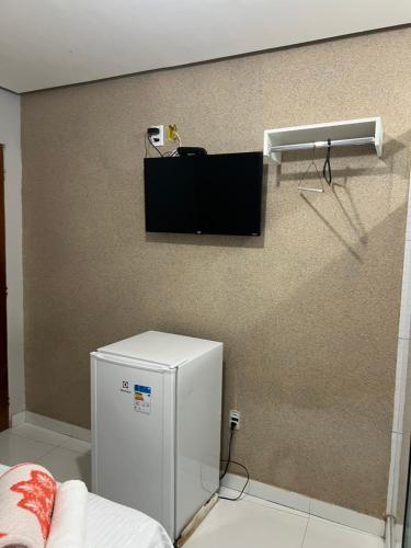 a room with a refrigerator and a tv on a wall at Hotel Santa Rita in Amarante do Maranhão