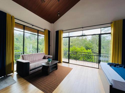 a living room with a bed and a couch and windows at Ella White Tea Garden Hotel in Ella