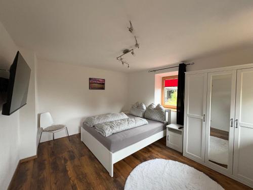 a white bedroom with a bed and a window at FeWo Landidyll in Dürrnberg