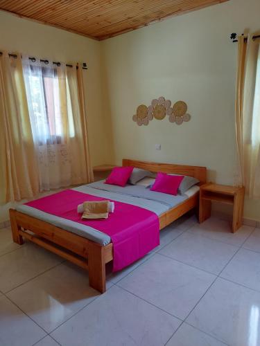 a bedroom with a large bed with pink sheets at Kambana Résidence in Ranomafana