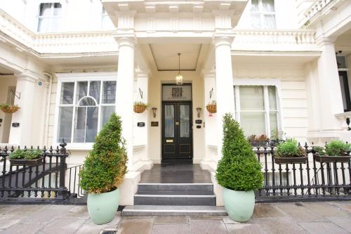 a white house with a black door and some plants at MSK Premium in London