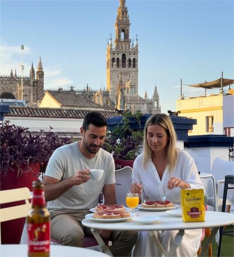a man and woman sitting at a table with plates of food at Rio Hostel in Seville