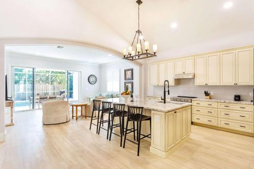 a kitchen with white cabinets and a island with bar stools at Imola Vacation Rental - Remodeled Pool Home Minutes from Vanderbilt Beach! Family-Friendly Retreat with 4 BR 4 BA and Private Screened Pool! in Naples