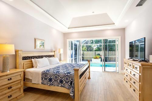 a bedroom with a bed and a tv and a window at Imola Vacation Rental - Remodeled Pool Home Minutes from Vanderbilt Beach! Family-Friendly Retreat with 4 BR 4 BA and Private Screened Pool! in Naples