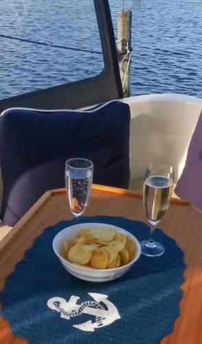 a table with a bowl of food and two glasses of water at Sleeping on the GilgaBoat! in Nakskov