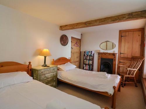 a bedroom with two beds and a fireplace at Rope Cottage in Bridport