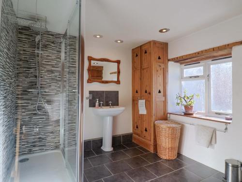 a bathroom with a glass shower and a sink at Rope Cottage in Bridport