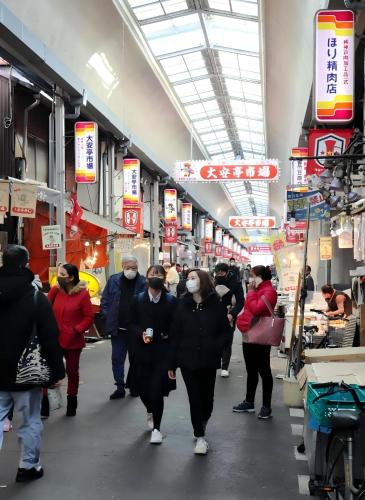 people wearing face masks walk through a food market at Kobe Youth Hostel in Kobe