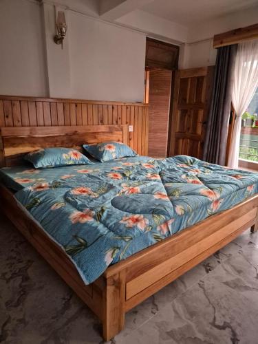 a large bed with a blue comforter with flowers on it at Pranavan Homestay in Mirik