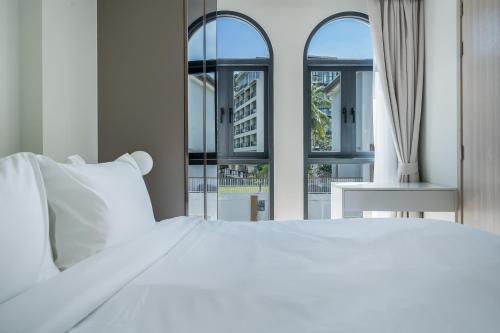 a bedroom with a white bed and two windows at Palmetto Park Residence in Karon Beach