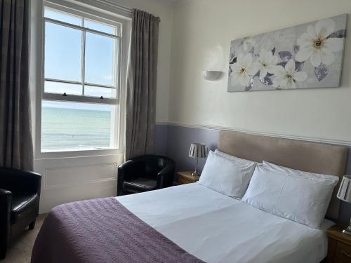 a bedroom with a bed and a window with the ocean at The Lindum in Hastings