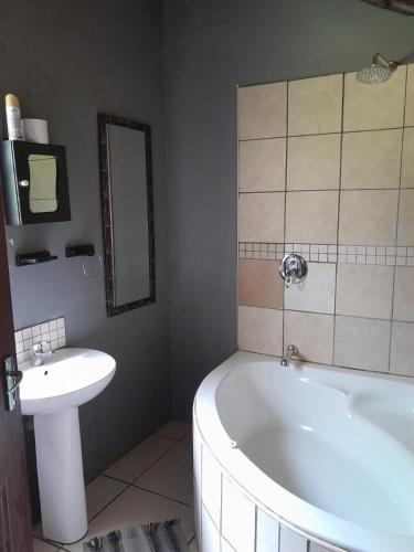 a bathroom with a bath tub and a sink at Warembo Lodge in Grootvlei