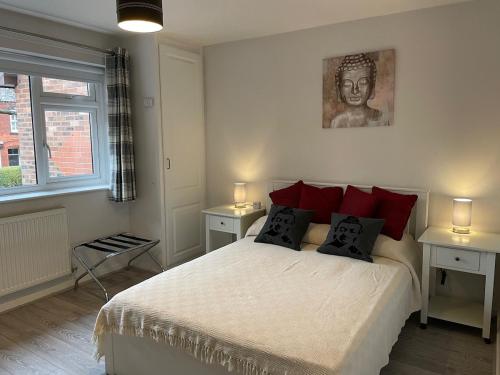 a bedroom with a bed with red pillows and a statue at The Mews in the heart of Stockton Heath in Warrington