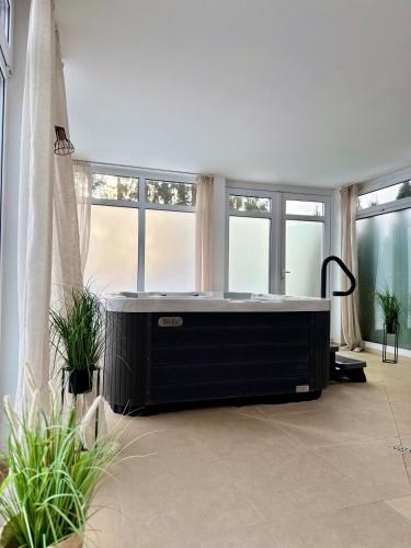 a bath tub in a room with windows at Al-Dom Apartamenty, SUN w Welle z dostępem do sauny i jacuzzi in Grzybowo