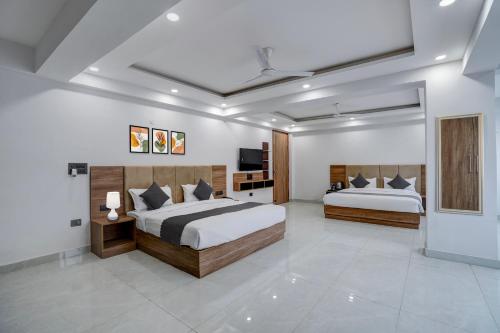 a bedroom with two beds and a television in it at Banquesta Suites in Noida