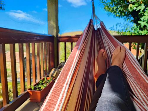 a person laying in a hammock on a porch at Casa do Rio, Natureza - Nova Gestão in Melgaço