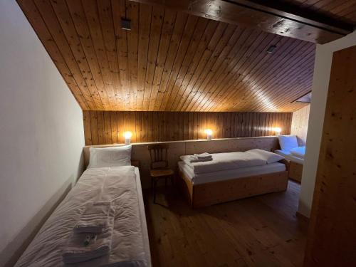 a bedroom with two beds and a wooden ceiling at Sust Lodge in Hospental