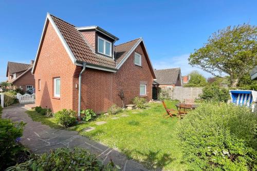 a brick house with a yard with a table and chairs at Ferienhaus Eibenweg 6 in Tinnum