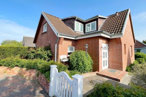 a brick house with a white fence at Ferienhaus Eibenweg 6 in Tinnum