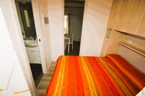 a bedroom with a bed with an orange blanket at VILLAGGIO TURISTICO LA FOCE SpA in Toscolano Maderno