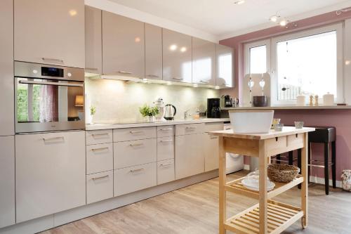 a kitchen with white cabinets and a wooden table at Instenweg 14 Fischhus in Rettin