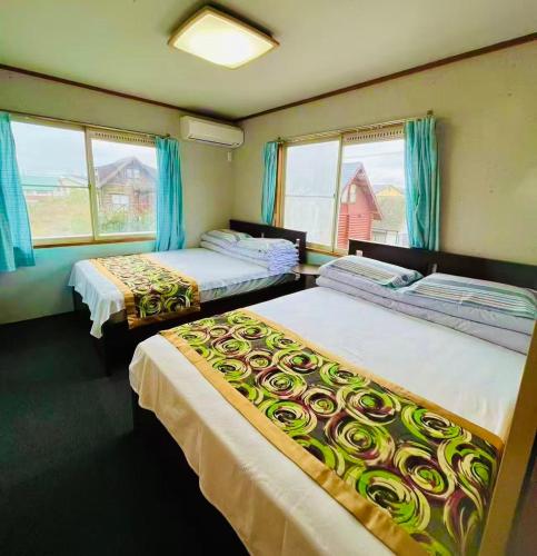 three beds in a room with blue curtains and windows at Biwa Takashima BBQ可 近湖周道路 in Takashima
