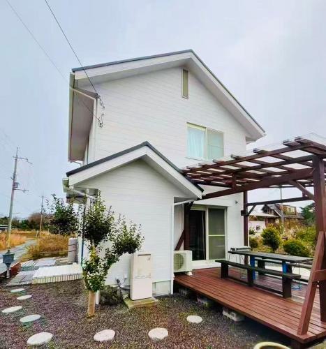 a white house with a wooden deck in front of it at Biwa Takashima BBQ可 近湖周道路 in Takashima