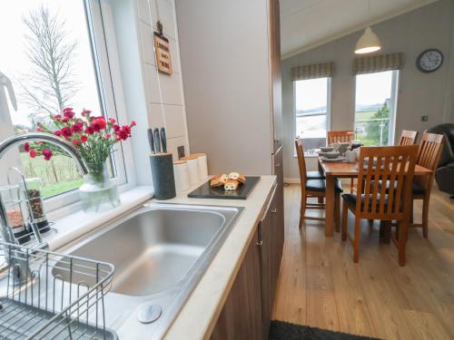 a kitchen with a sink and a dining table at Holly Lodge in Holywell