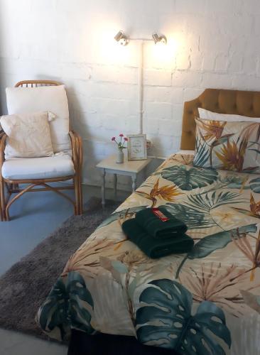 a bedroom with a bed and a chair and a lamp at 19 on Robyn in Durbanville
