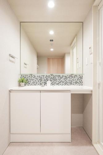 a bathroom with white cabinets and a large mirror at Seed INN Haneda Terrace 301 in Tokyo