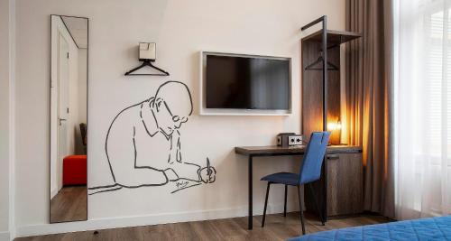 a room with a desk and a tv on a wall at Berlage Hotel, BW Signature Collection in The Hague