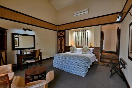 a bedroom with a bed and a table and chairs at Glenburn Lodge & Spa in Muldersdrift