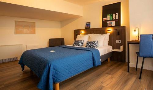 a hotel room with a bed with a blue blanket at Berlage Hotel, BW Signature Collection in The Hague