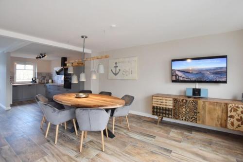 a kitchen and dining room with a wooden table and chairs at Ferienhaus Erika in Tinnum