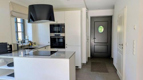 eine Küche mit weißen Arbeitsplatten und einer schwarzen Tür in der Unterkunft Ferienhaus Calluna Stilvolle Doppelhaushälfte in der Lüneburger Heide, Hunde willkommen in Winsen