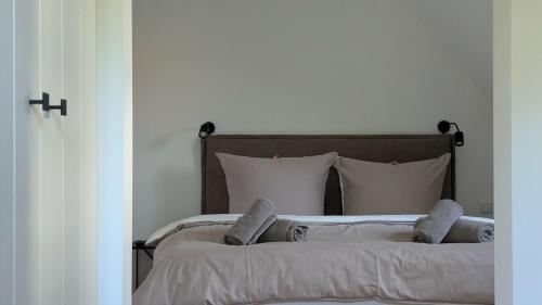 ein Bett mit weißen Laken und Kissen in einem Schlafzimmer in der Unterkunft Ferienhaus Calluna Stilvolle Doppelhaushälfte in der Lüneburger Heide, Hunde willkommen in Winsen