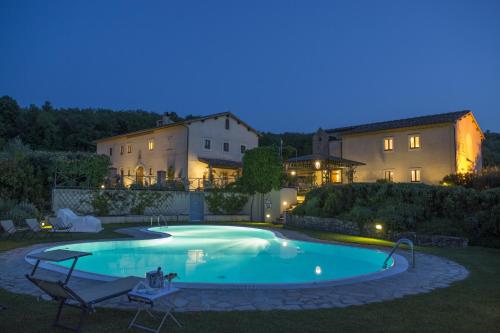 a swimming pool in the yard of a house at night at Relais Osteria Dell'Orcia in Bagno Vignoni